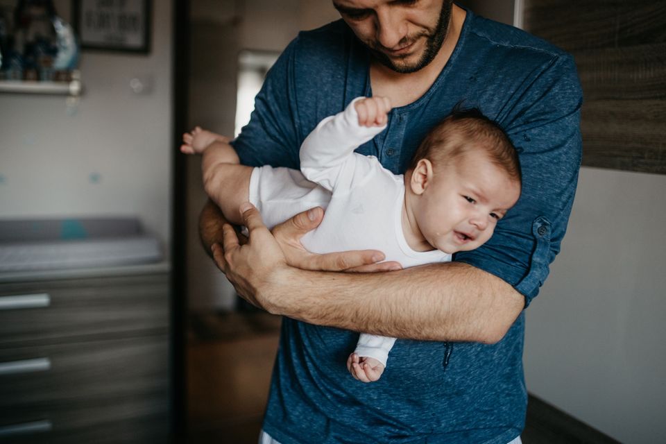 Vater trägt Baby im Fliegergriff