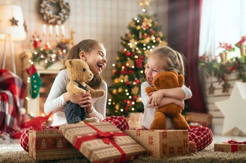 Zwei Mädchen packen begeistert ihre Weihnachtsgeschenke aus