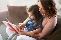 Mama liest ihrer Tochter ein Buch vor
