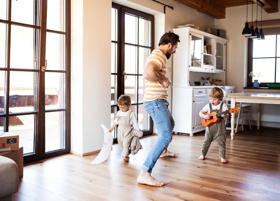 Ein Vater macht mit seinen zwei Kleinkindern zuhause Musik