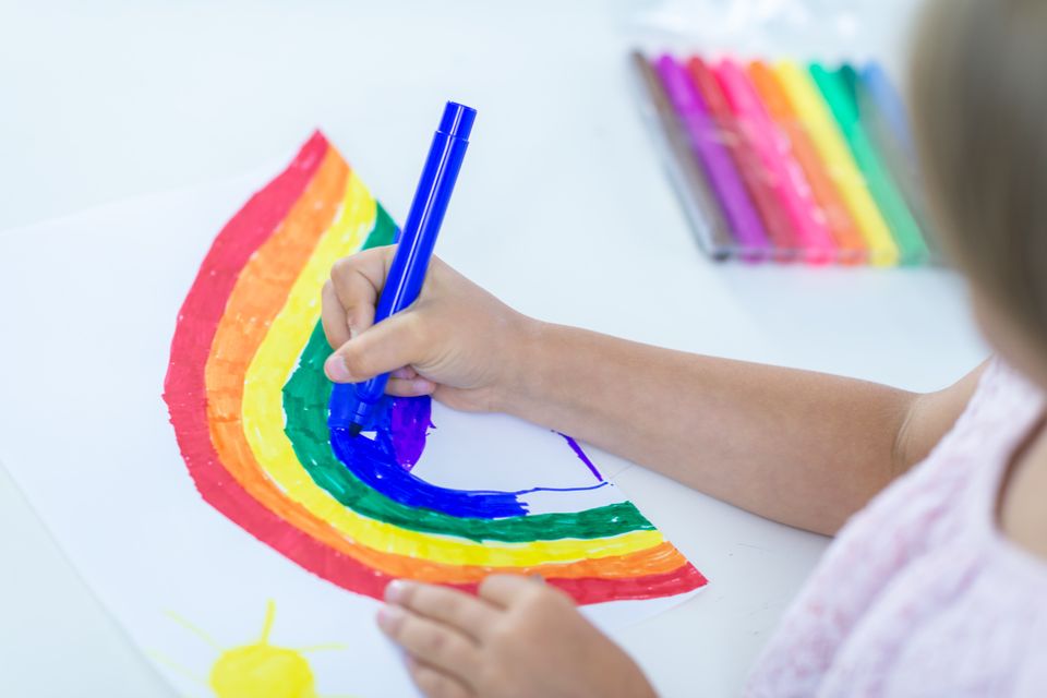 Ein Kind malt einen Regenbogen