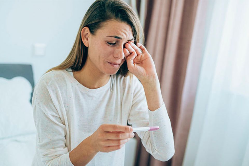 Frau weint Schwangerschaftstest