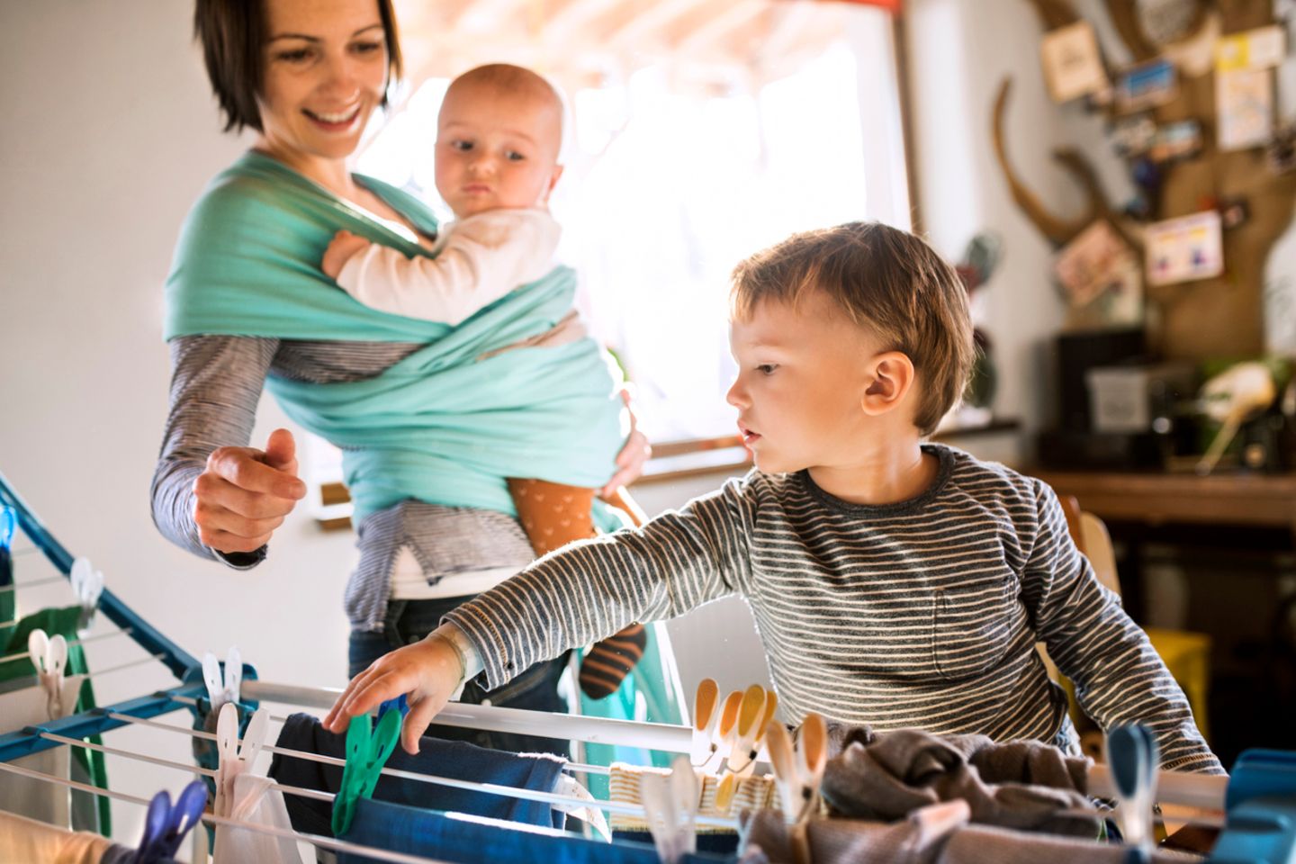 Mutter und Kind hängen im Zimmer Wäsche auf