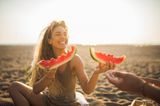 Frau am Strand isst Wassermelone