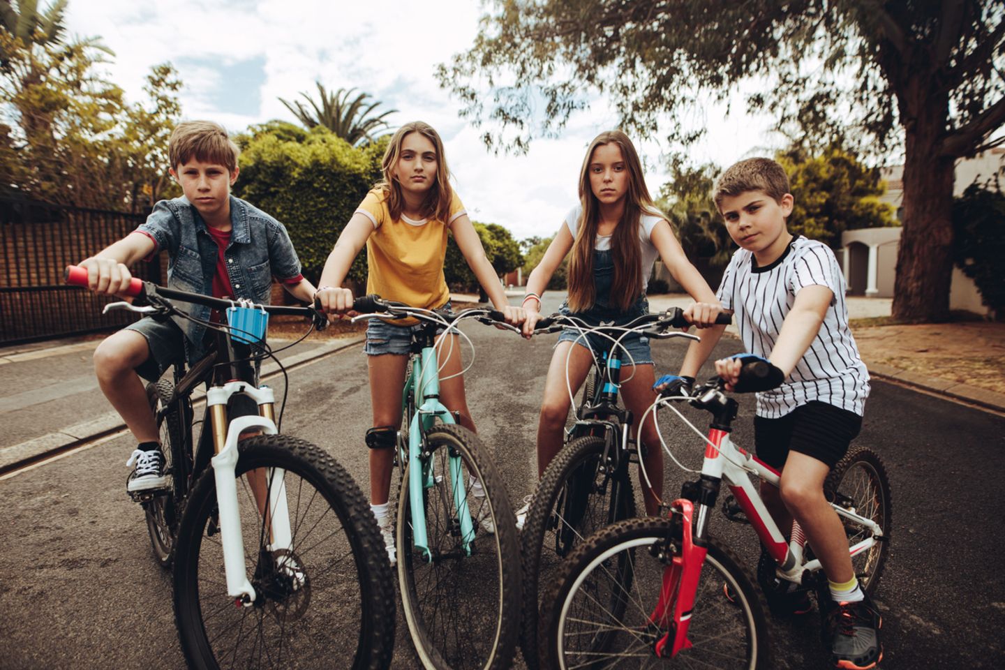 Vier Kinder auf Fahrrädern gucken in die Kamera