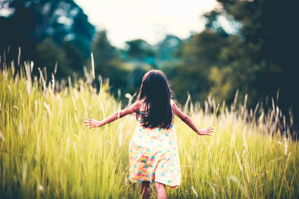 Kind läuft durch hohes Gras