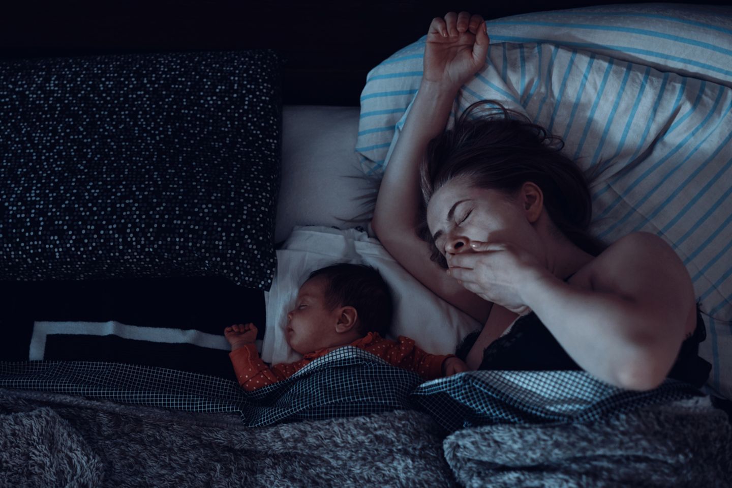 Frau gähnt, Baby schläft neben ihr