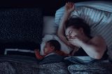 Frau gähnt, Baby schläft neben ihr