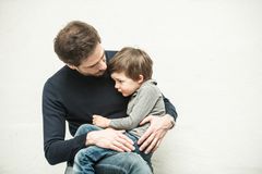 Mann hat einen Jungen auf dem Schoß und tröstet ihn