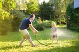 Vater und Kind spielen mit Gartenschlauch