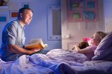 Vater liest Tochter eine Gute-Nacht-Geschichte vor
