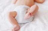 Fieber messen: Ein Baby, das nur eine Windel trägt, strampelt mit den Beinchen