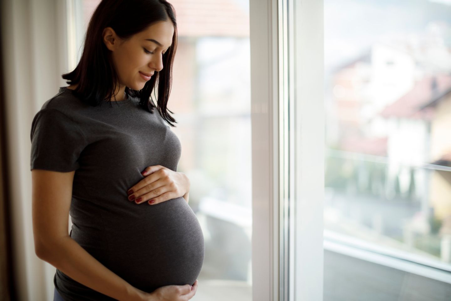 Schwangere Frau schaut auf ihren Bauch