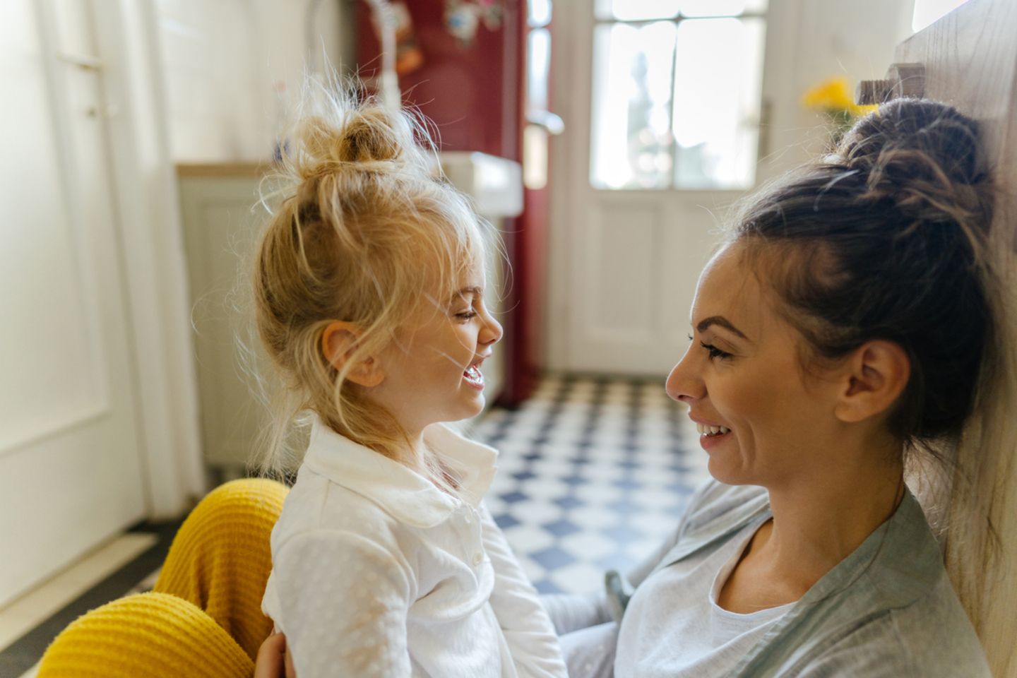 Mutter und Kind sitzen in der Küche auf dem Boden Mutter und Kind sitzen in der Küche auf dem Boden