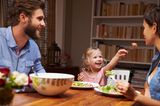 Tochter füttert Mutter am Esstisch