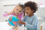 Zwei Kinder spielen mit einem Globus