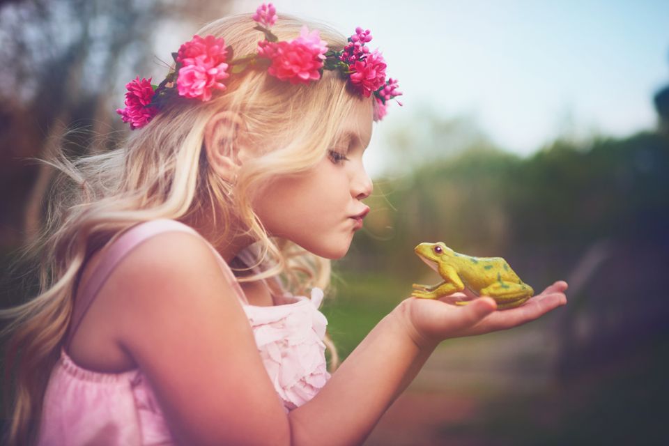 Kleines Mädchen küsst einen Frosch