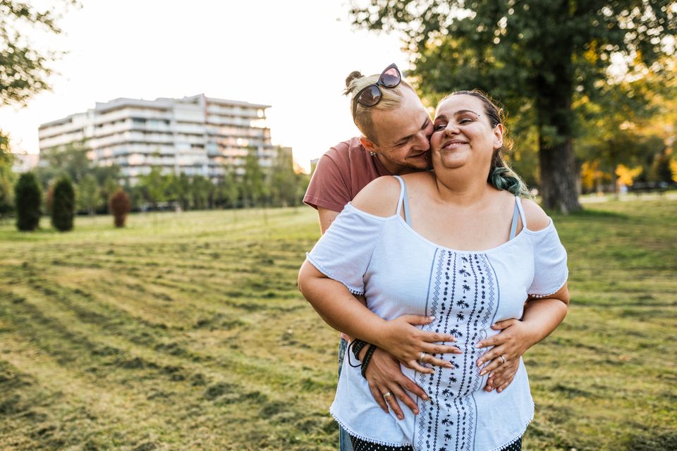 Plussize Schwangere wird von ihrem Freund umarmt