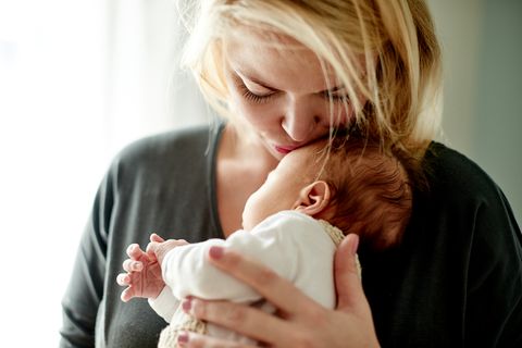 Mutter hält neugeborenes Baby im Arm