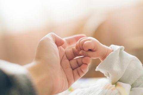 Reflexe Baby: Neugeborenes umklammert den Finger seiner Mutter