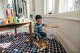 Kleiner Junge räumt Spielfiguren in einen Korb