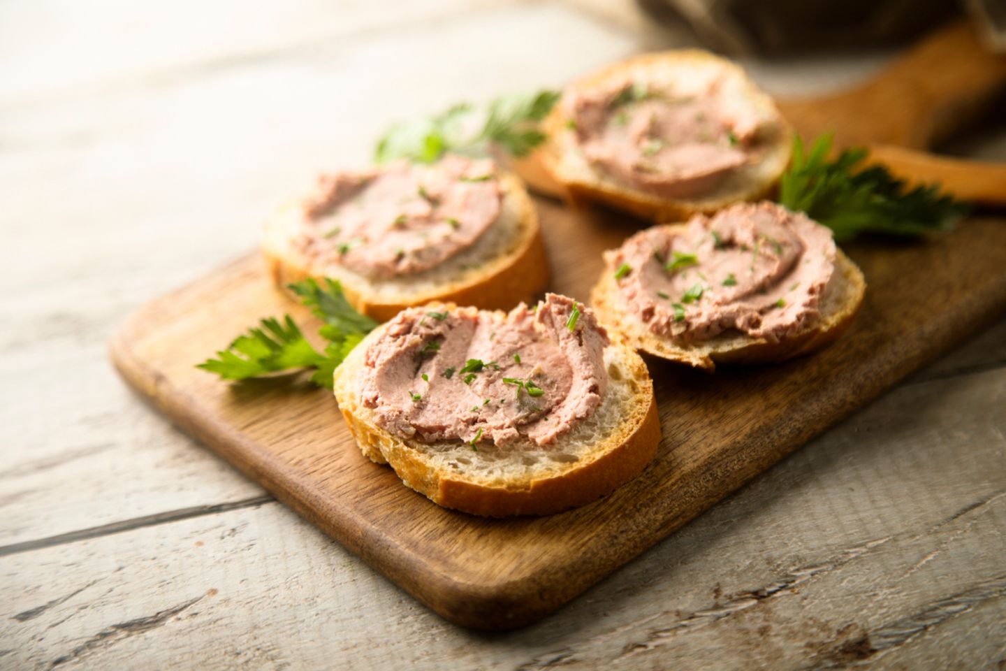 Zwei Scheiben Brot mit Leberwurst auf einem Brettchen