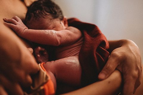 Ein neugeborenes Baby im Arm seiner Mutter