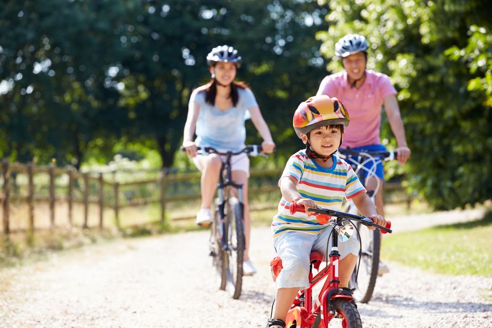 Kleine asiatische Familie fährt Fahrrad Kleine asiatische Familie fährt Fahrrad