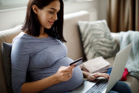 Schwangere sitzt auf dem Sofa beim Online-Shopping