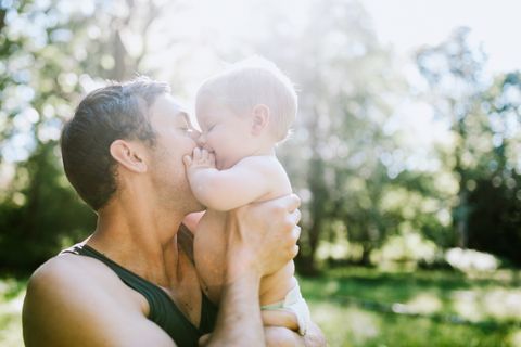 Hitzepickel bei Babys: Mann kuschelt mit einem Baby im Sonnenschein