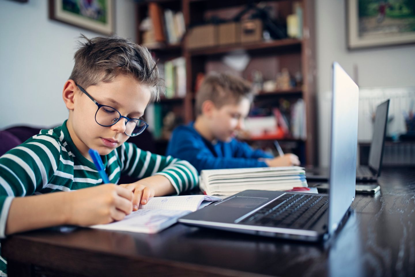 Zwei Jungen lernen im Fernunterricht mit Laptop und anderen Materialien
