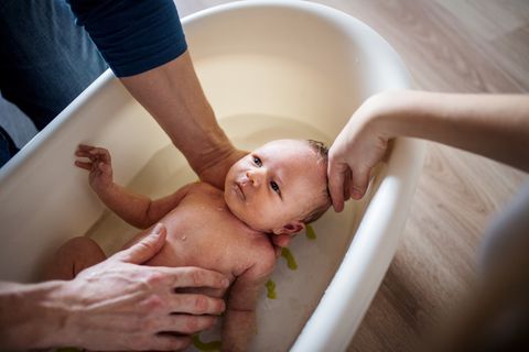 Baby wird von seinem Vater in einer Babywanne gebadet