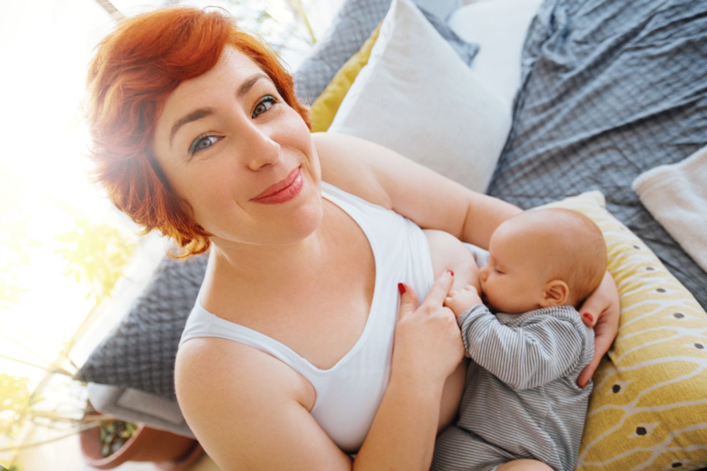 Hübsche rothaarige Mutter stillt ihr Baby fröhlich