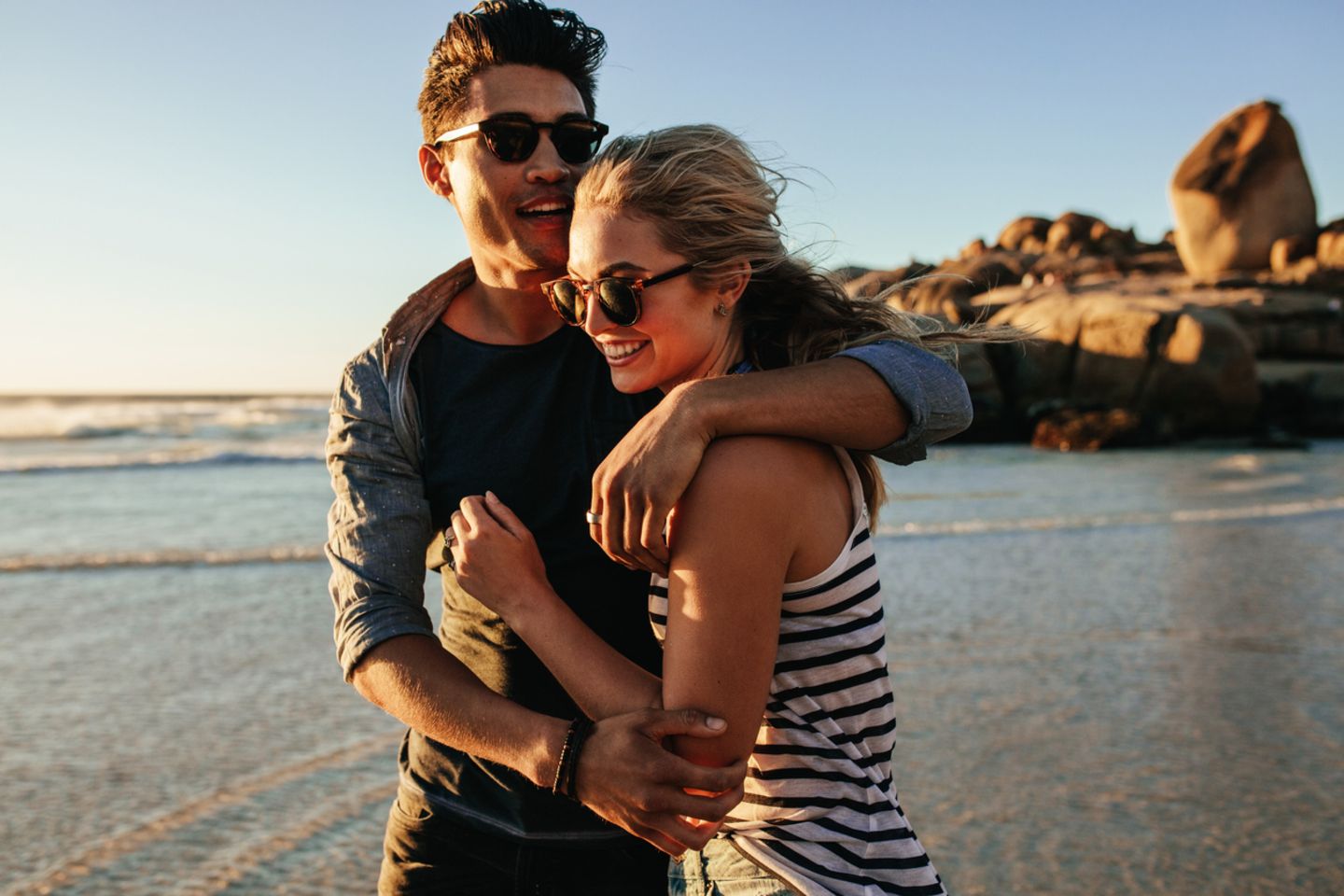 Junges verliebtes Paar geht im Sommer am Strand spazieren