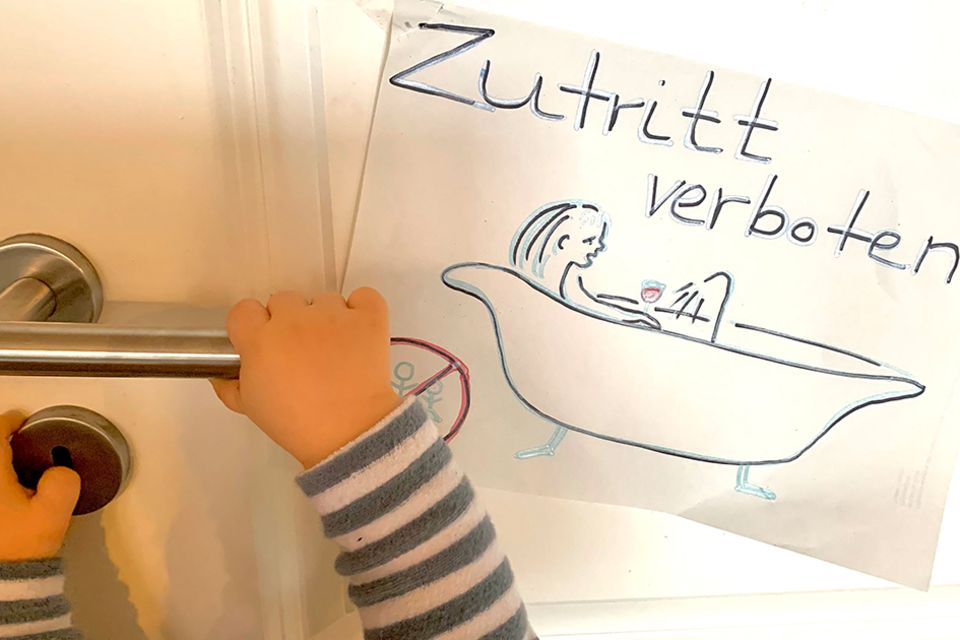 Schild am Badezimmer: "Zutritt verboten", darauf eine Zeichnung der badenden Mutter. Baby drückt die Türklinke runter.