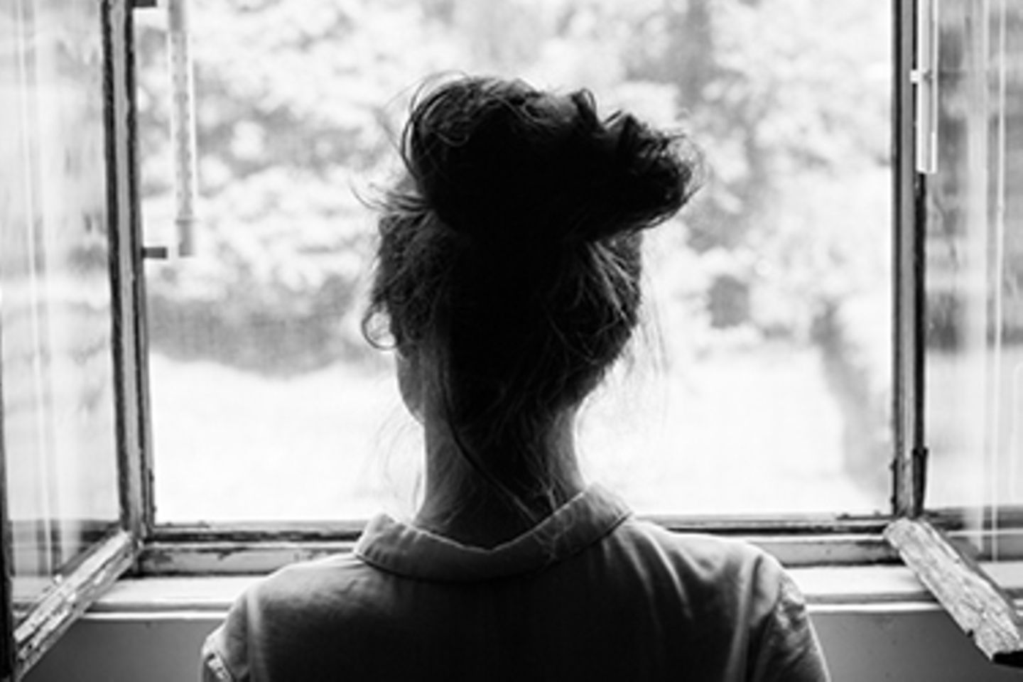 schwarz-weiß Bild einer Frau vor dem offenen Fenster