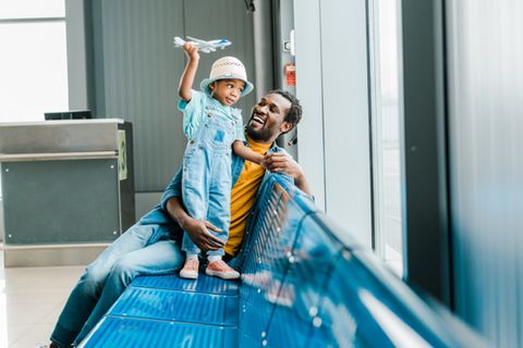 Ein Papa mit seinem kleinen Sohn und Kinderausweis am Flughafen.