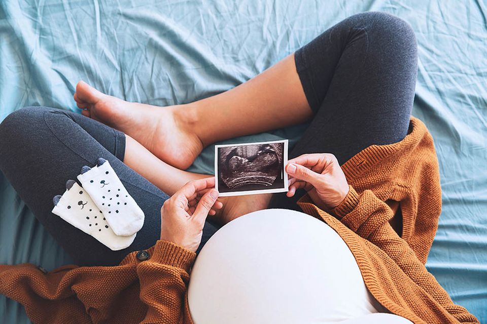 Schwangere betrachtet Ultraschallfoto ihres Babys