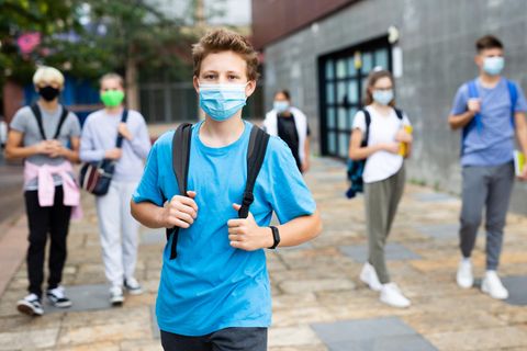 Schüler kommen aus der Schule und tragen medizinische MAsken