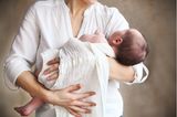 Baby wird mit einem Mulltuch im Arm von Mama getragen