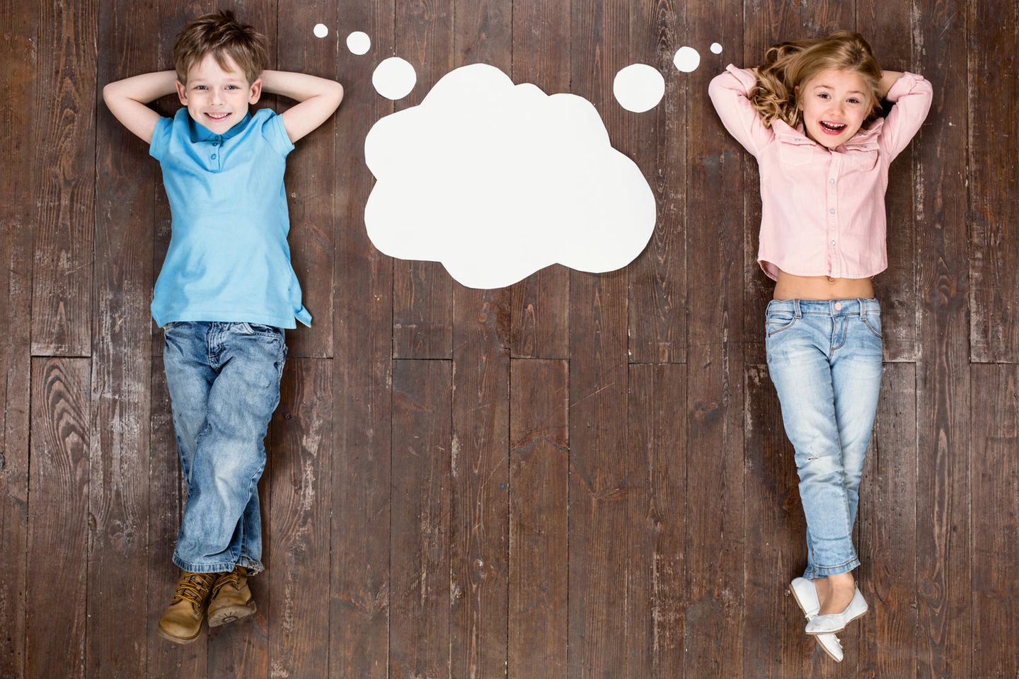 Zwei Kinder liegen auf dem Boden, zwischen ihnen eine Denkblase