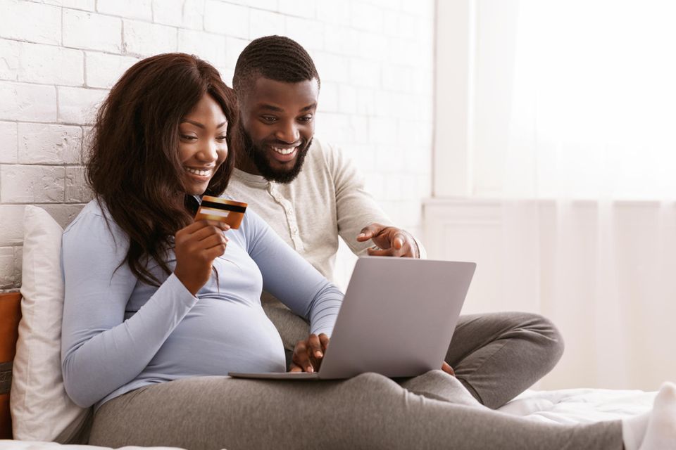 Schwangere und Ehemann kaufen am Laptop ein