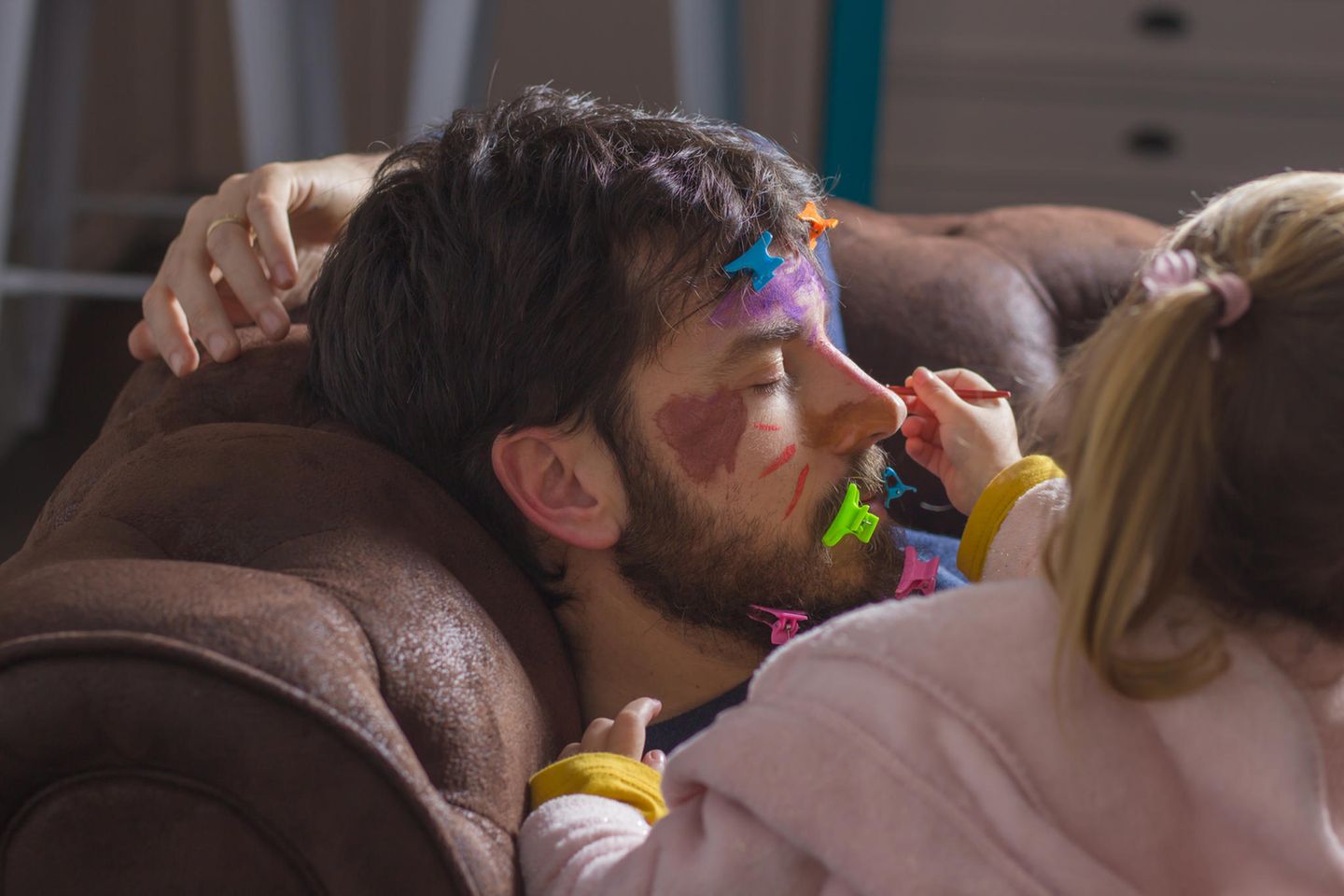 Papa schläft auf der Couch und Tochter malt ihn an