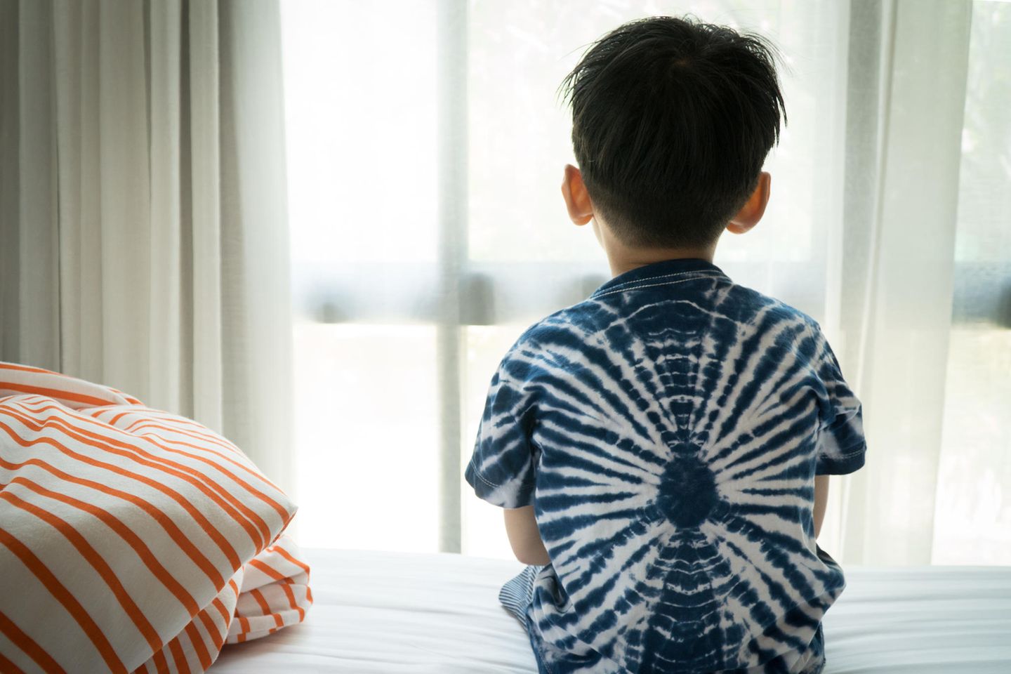 Kinderärzte warnen: Junge sitzt auf dem Bett