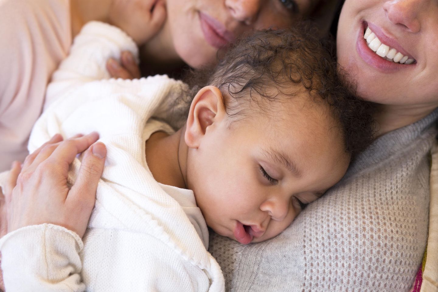 Stiefkindadoption: Zwei Mütter mit ihrem schlafenden Baby auf dem Arm