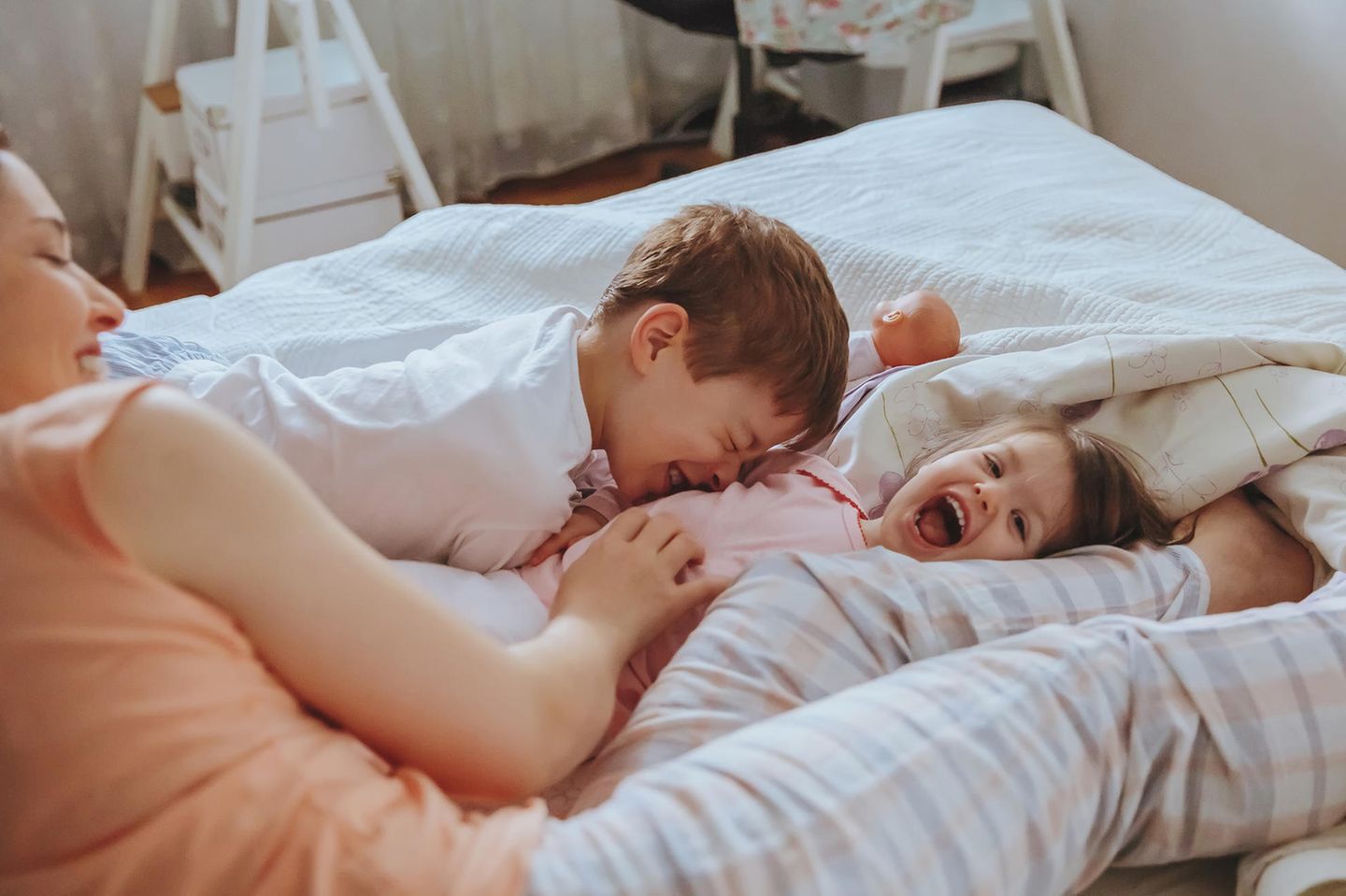 Kinder lachen mit Mama morgens im Bett