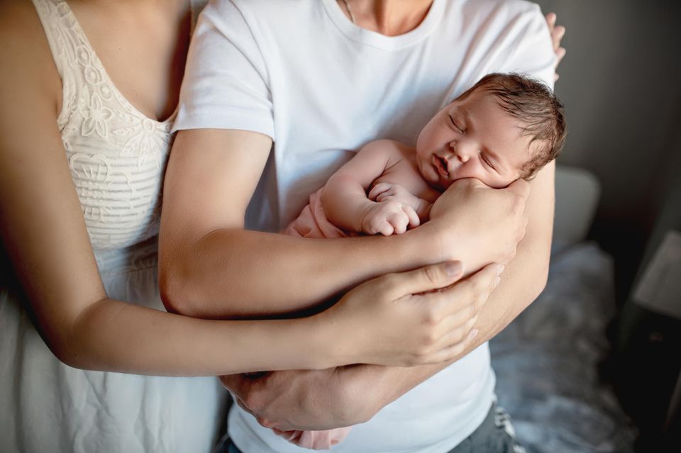 Nabelbruch beim Baby: Papa und Mama mit ihrem Neugeborenen auf dem Arm
