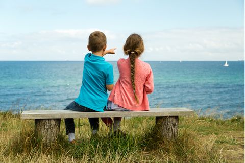 Nordische Namen: Mädchen und Junge auf einer Bank vor einem See.