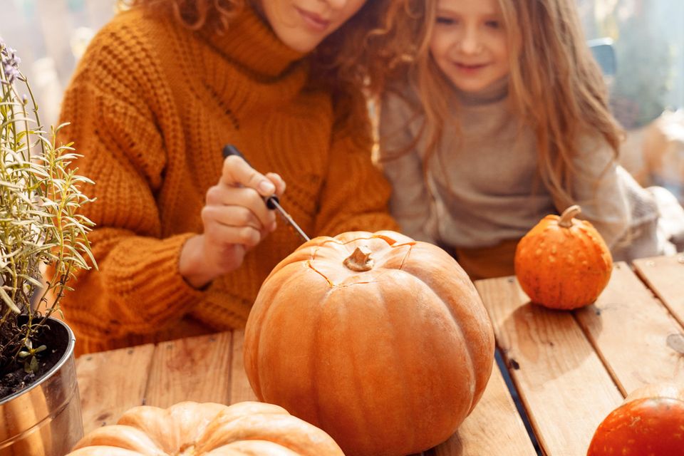 Mutter und Tochter schnitzen einen Halloween Kürbis