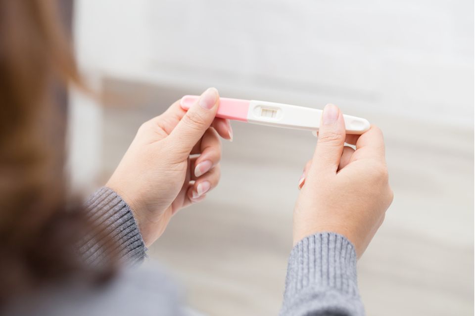 Schwangerschaftsanzeichen: Eine Frau hält einen positiven Schwangerschaftstest in den Händen
